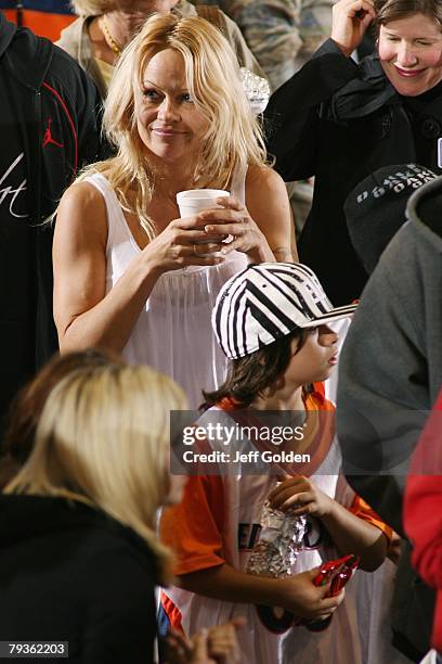 Actress Pamela Anderson returns to her seat with her son Dylan Jagger Lee after getting concessions before the basketball game between the Loyola...