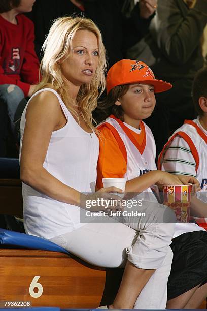 Actress Pamela Anderson sits with her son Brandon Thomas Lee before the basketball game between the Loyola Marymount Lions and the Pepperdine Waves...