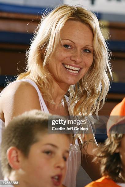 Actress Pamela Anderson laughs while sitting before the basketball game between the Loyola Marymount Lions and the Pepperdine Waves on January 26,...
