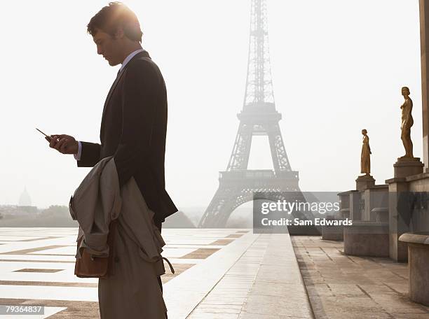 businessman outdoors with cellular phone by eiffel tower - samuser stock pictures, royalty-free photos & images