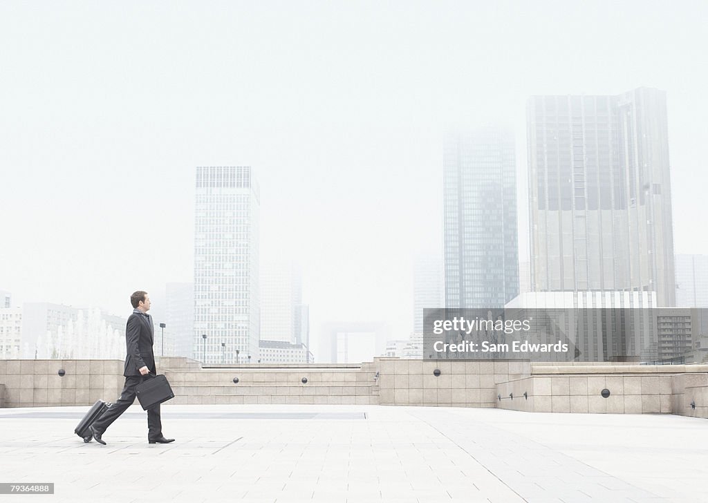 Businessman outdoors walking with luggage