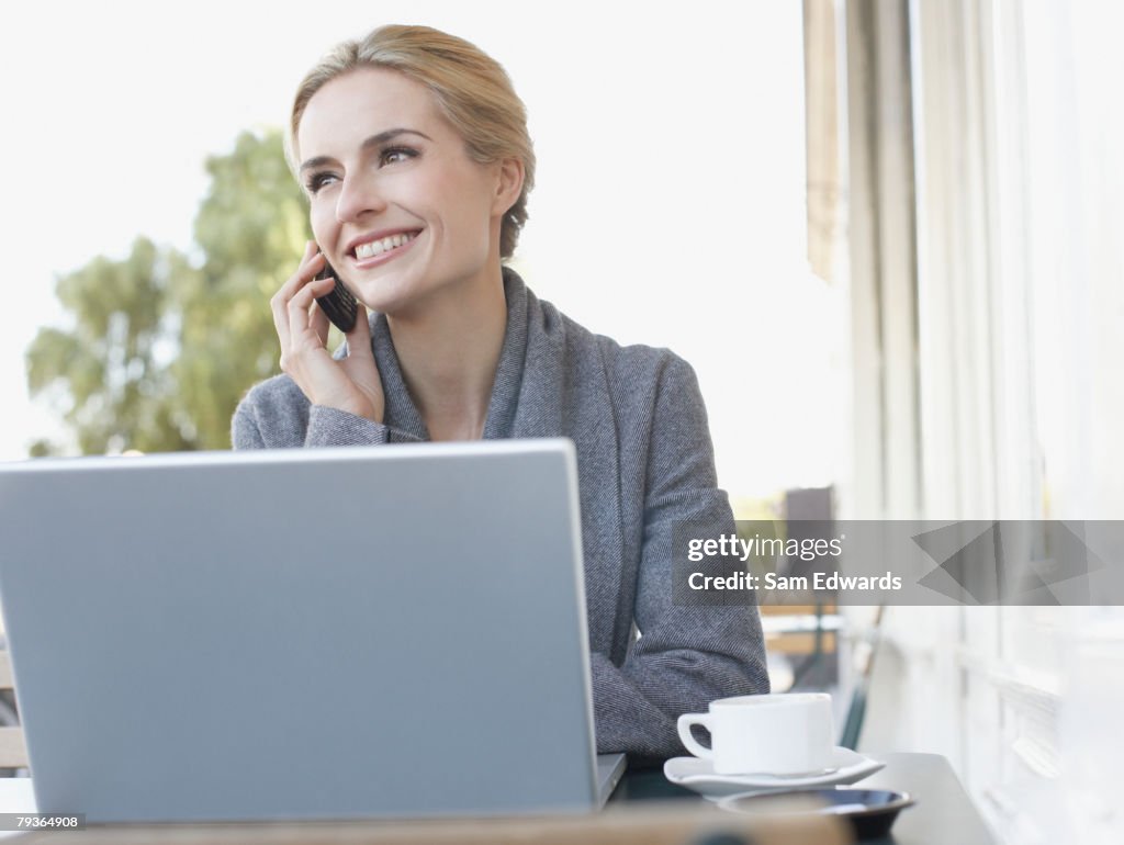 Woman outside a restaurant with a laptop and mobile phone