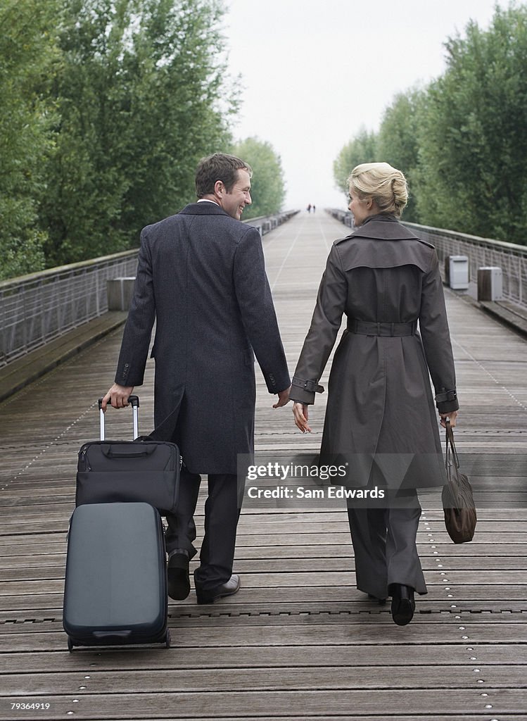 Two businesspeople walking on bridge with luggage