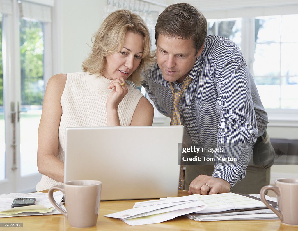 Couple in kitchen with laptop and paperwork