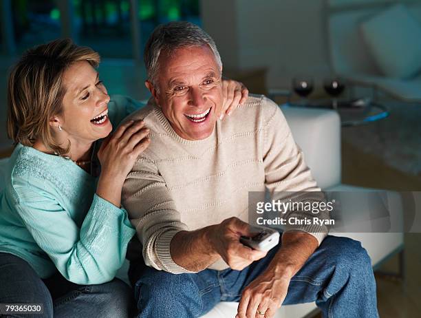 couple in living room watching television and laughing - watching tv couple night stock pictures, royalty-free photos & images