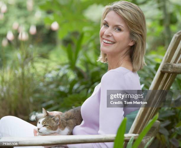 frau im freien im hof mit katze auf ihrem schoß - frau 50 garten stock-fotos und bilder