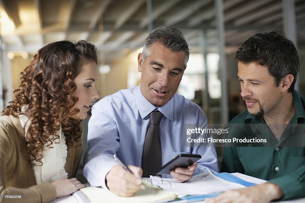 Three businesspeople in office with paperwork