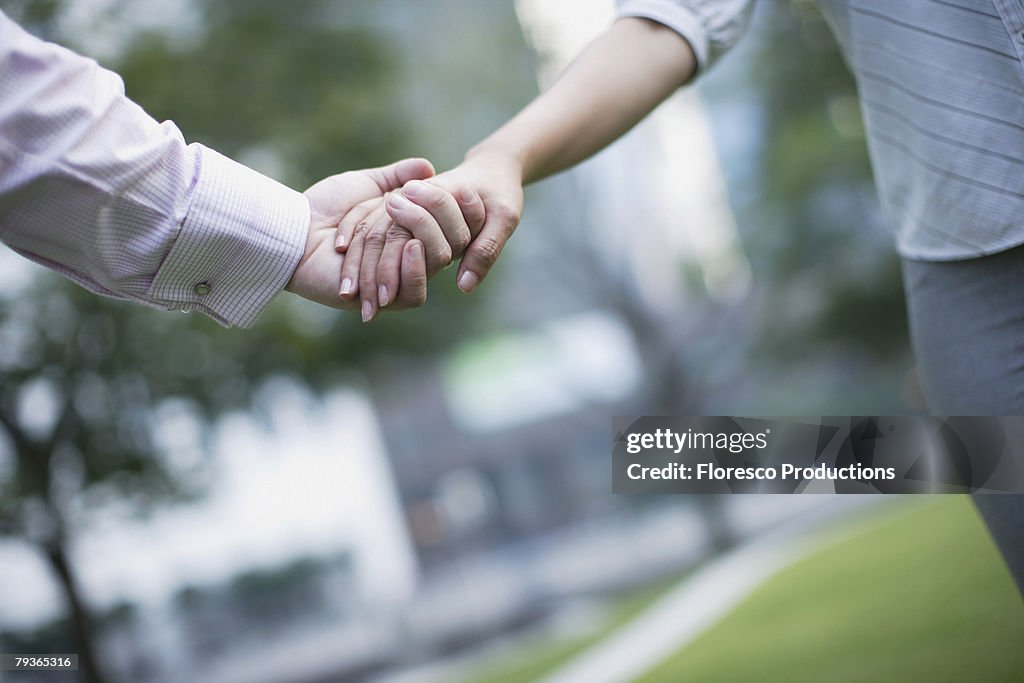 Two businesspeople outdoors holding hands