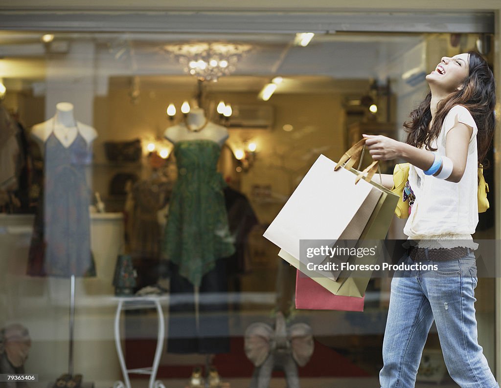 Woman outdoors with shopping bags laughing