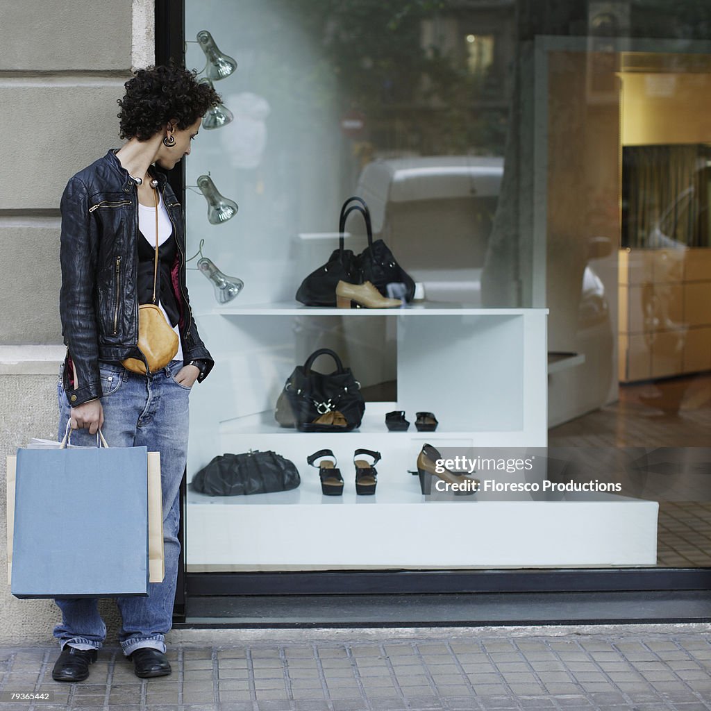 Woman outdoors holding shopping bags and window shopping