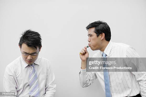 businessman indoors blowing whistle beside other businessman - whistle blower stock pictures, royalty-free photos & images