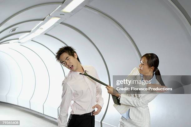 businesswoman slapping businessman in corridor - ohrfeige stock-fotos und bilder