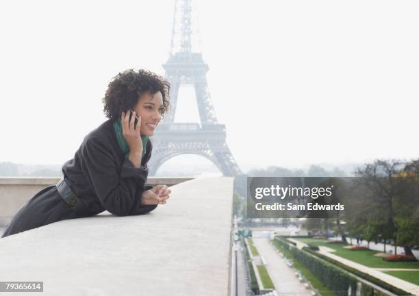 woman outdoors on her mobile phone by the eiffel tower - french women stock pictures, royalty-free photos & images