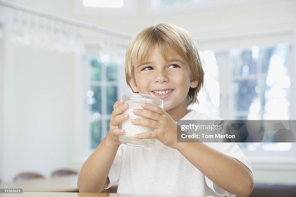 Young boy in kitchen drinking glass of milk