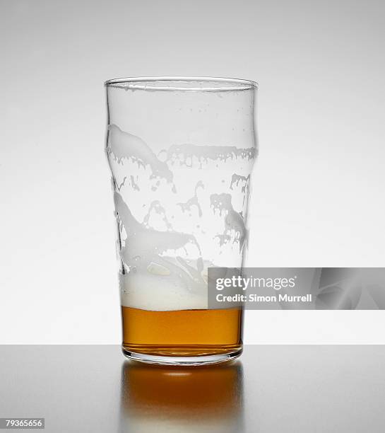 almost empty glass of beer indoors - half ストックフォトと画像