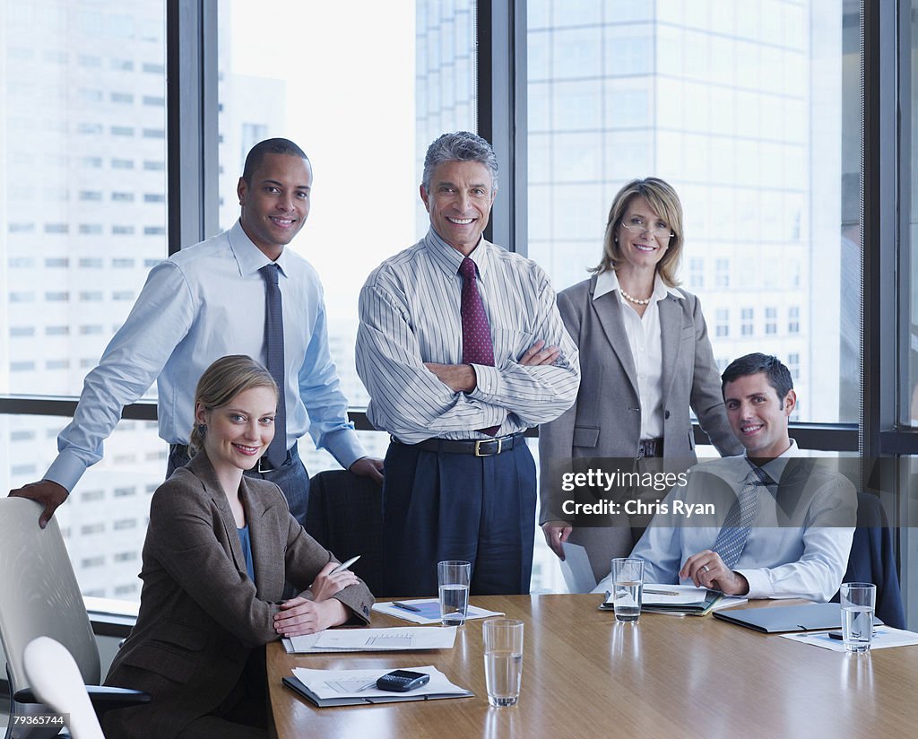 Five businesspeople in a boardroom looking at camera
