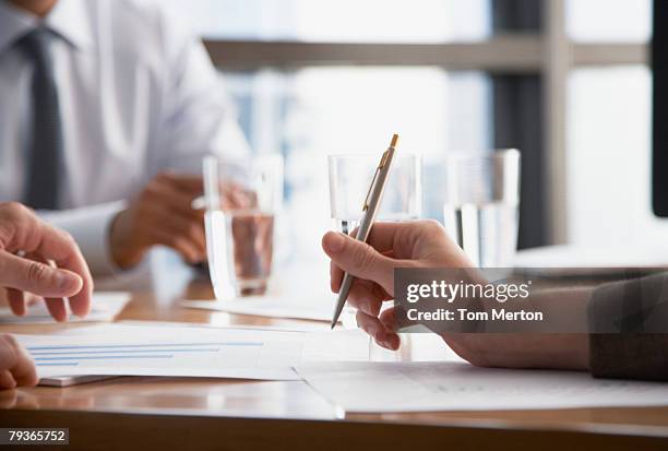 three businesspeople at a boardroom table - hand glasses stockfoto's en -beelden