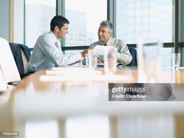 zwei geschäftsleute in einer boardroom arbeiten - fokus-auf-den-hintergrund stock-fotos und bilder