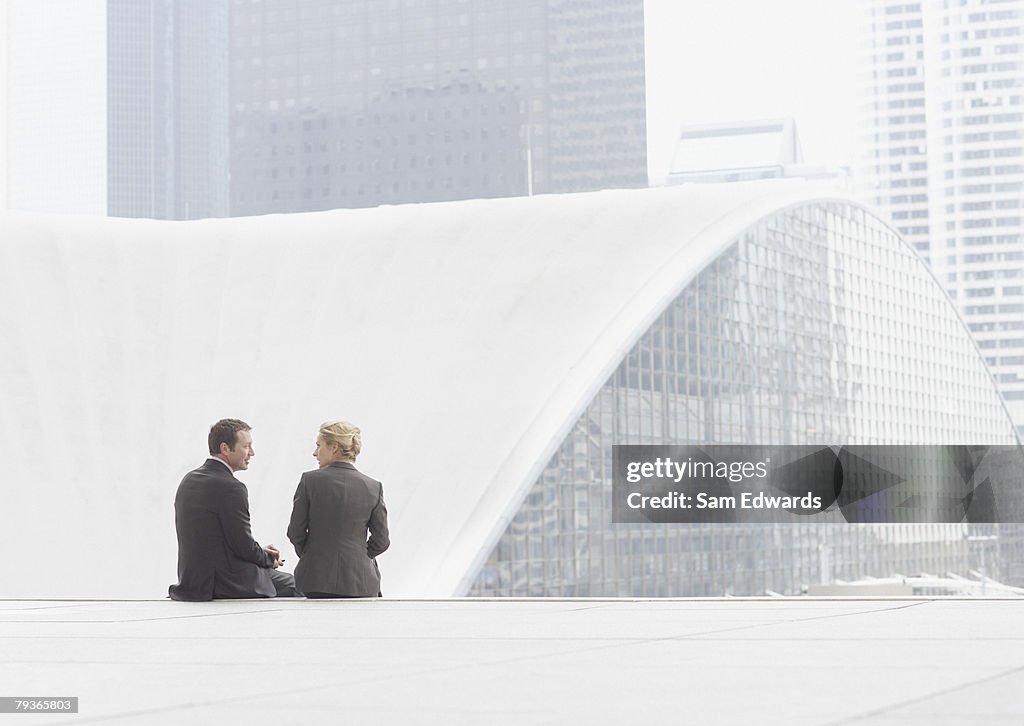 Two businesspeople sitting outdoors on step