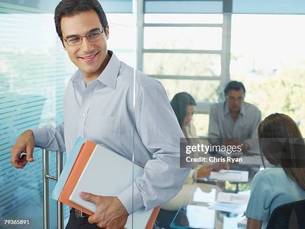 businessman leaving boardroom with three businesspeople in background - four people walking away stock pictures, royalty-free photos & images