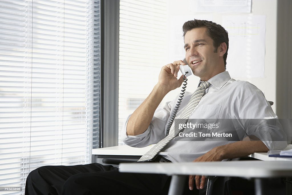 ビジネスマンオフィスで電話で、大型の窓