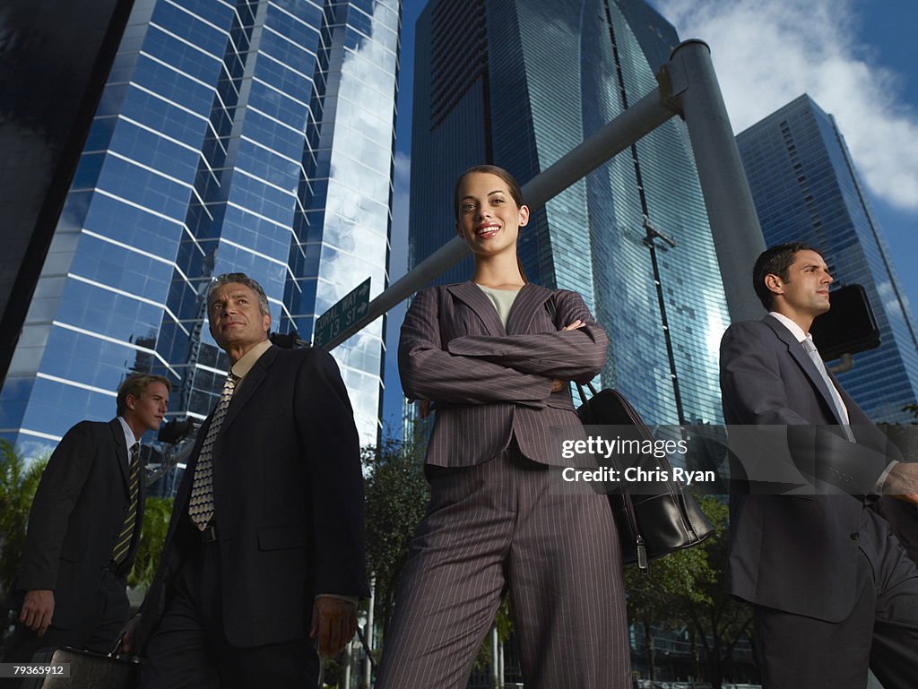 Femme d'affaires à l'extérieur en regardant la caméra avec trois businesspeop