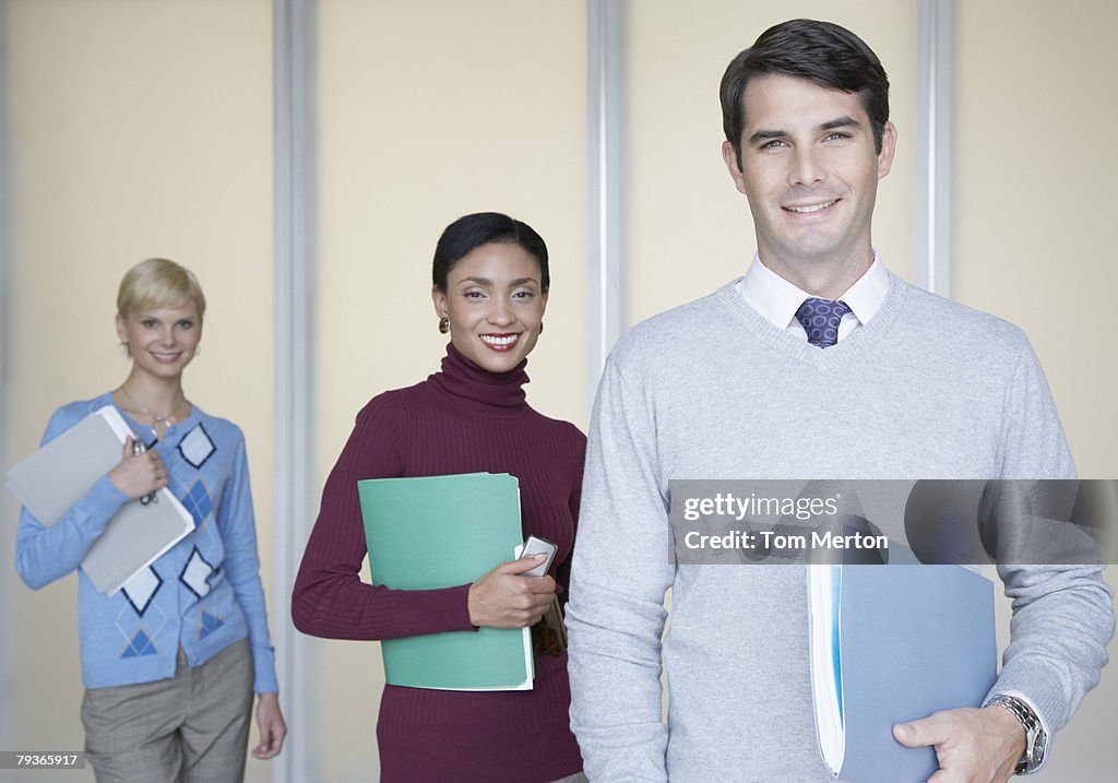 Three businesspeople in office looking at camera