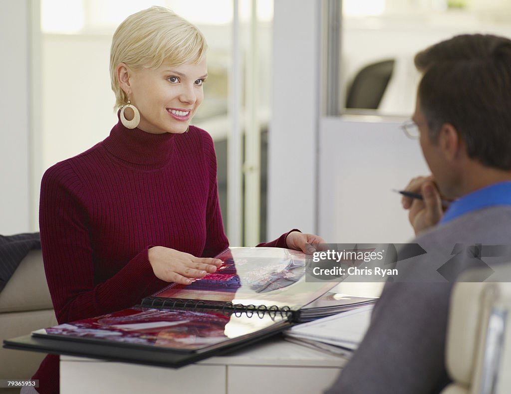 Two businesspeople in office looking at an album