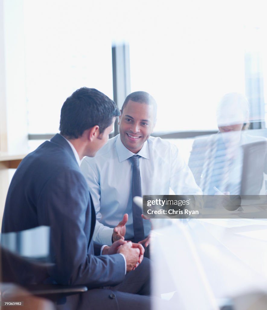 Three businesspeople in boardroom through glass