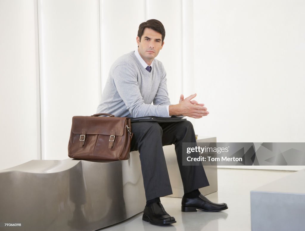 Businessman sitting in office lobby looking at camera