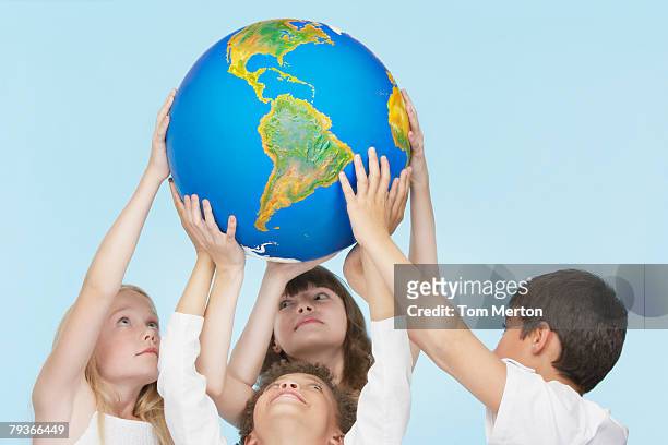 five children holding up a globe indoors - world children day stock pictures, royalty-free photos & images
