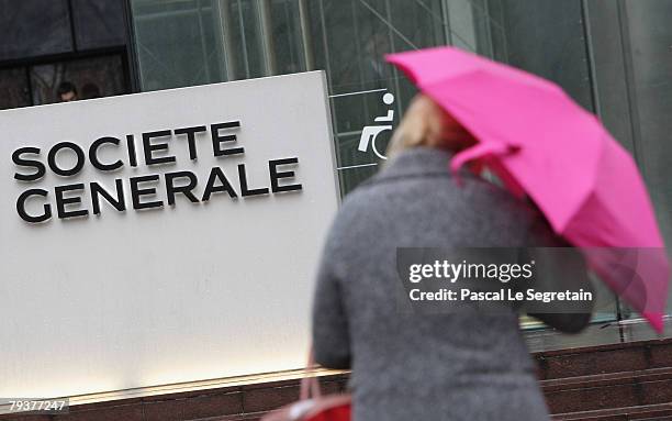 Societe Generale employee walks past the Societe Generale bank logo in front of the entrance of its headquarters on January 30, 2008 in La Defense...