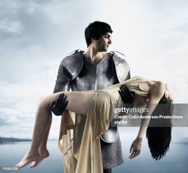 mixed race man in suit of armor carrying woman - ritter stock-fotos und bilder