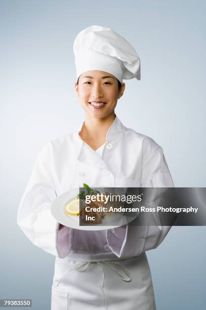 asian female chef holding plate of food - lady hut studio stock-fotos und bilder