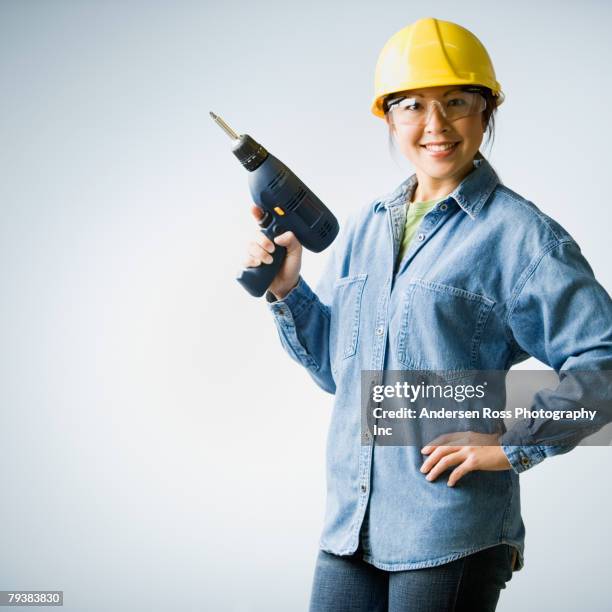 asian woman holding cordless drill - builder standing isolated stock-fotos und bilder