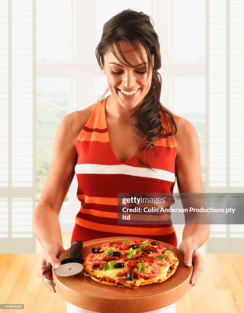 Hispanic woman holding homemade pizza