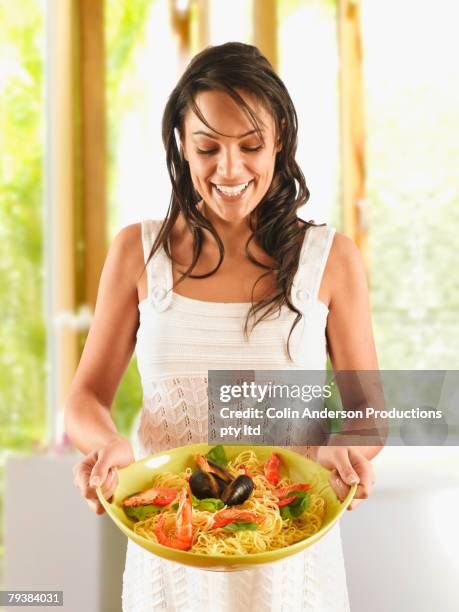 hispanic woman holding plate of pasta - basil ltd stock pictures, royalty-free photos & images