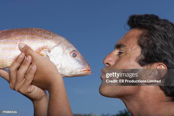 hispanic man pursing lips at fish - blue lips stock pictures, royalty-free photos & images