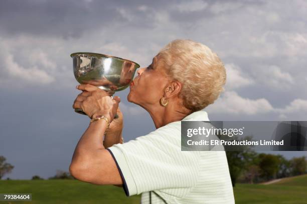 senior african american woman kissing golf trophy - kiss the trophy stock pictures, royalty-free photos & images