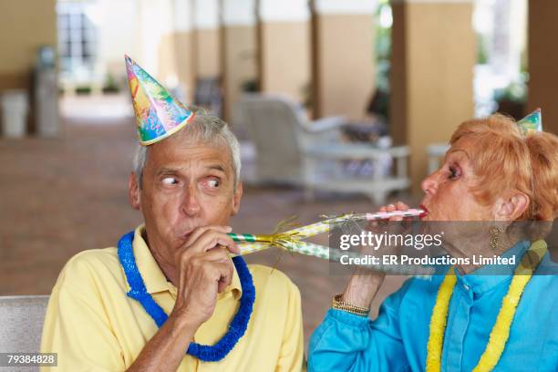 senior couple at birthday party - party horn blower stock pictures, royalty-free photos & images