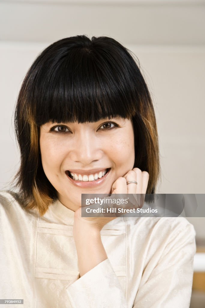 Asian woman resting chin on hand