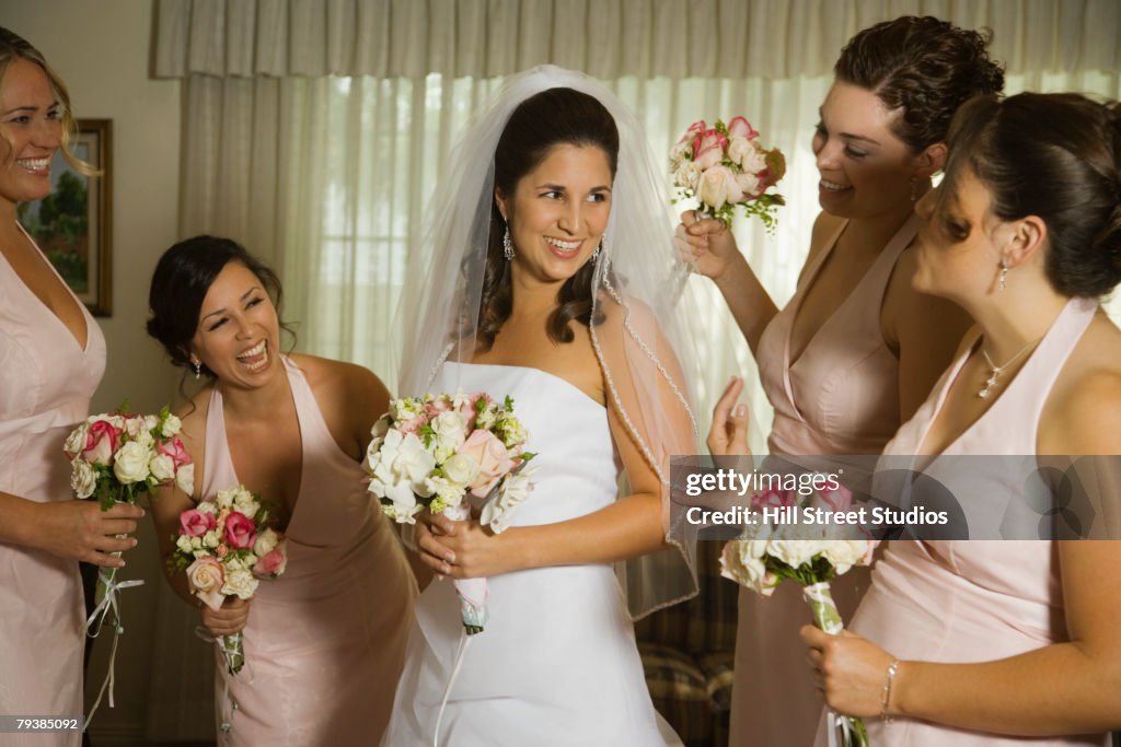 Hispanic bride and bridesmaids laughing