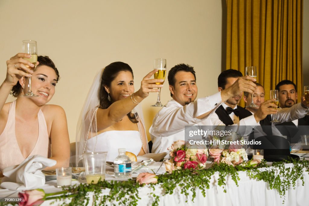 Hispanic newlyweds toasting with champagne