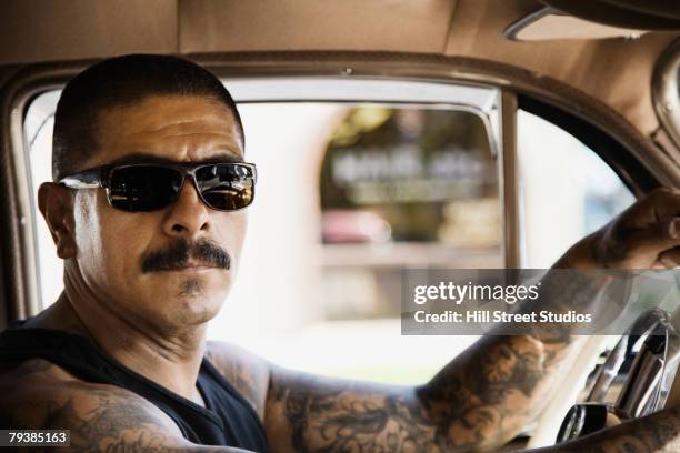 tattooed hispanic man driving car - low rider stock pictures, royalty-free photos & images