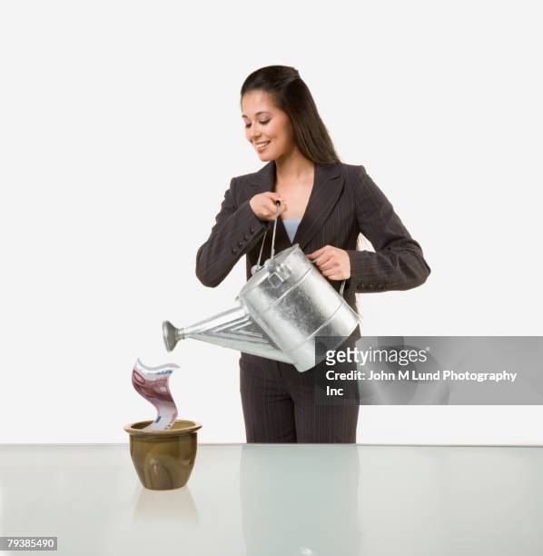 mixed race businesswoman watering money in planter - holding watering can stock pictures, royalty-free photos & images
