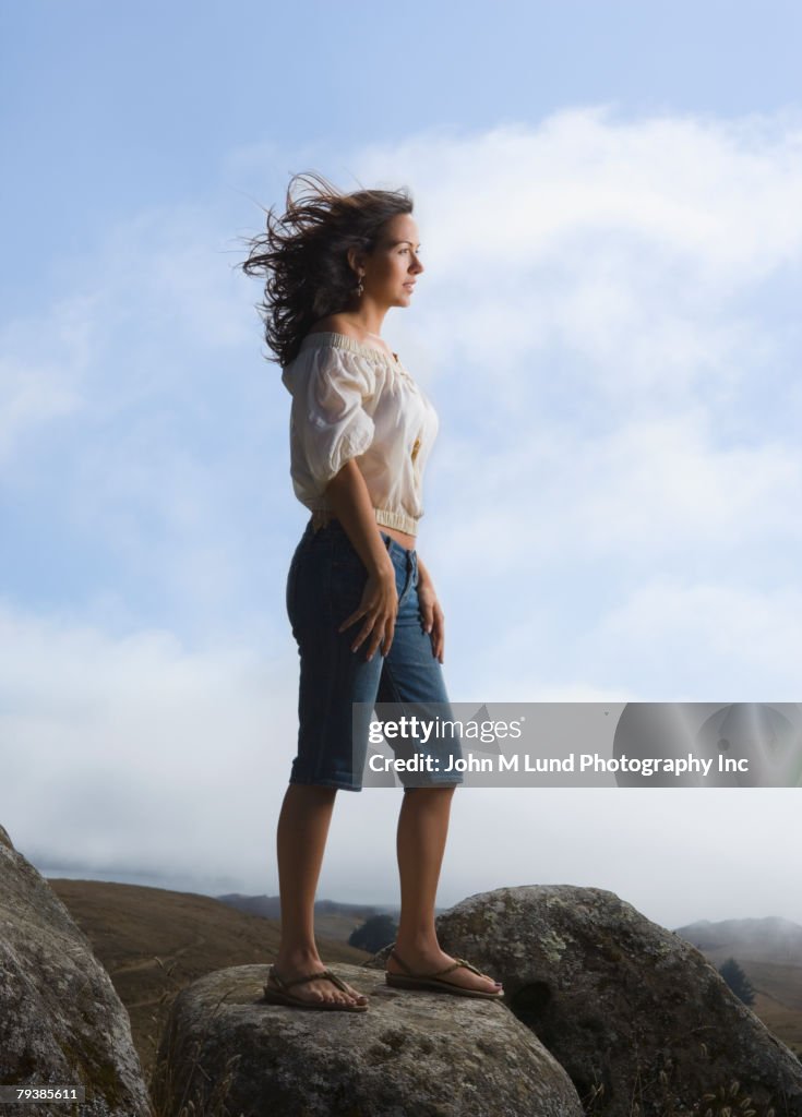 Hispanic woman standing on rock