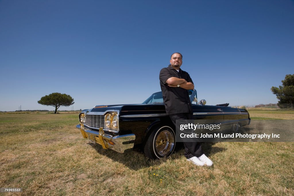 Hispanic man leaning on low rider car