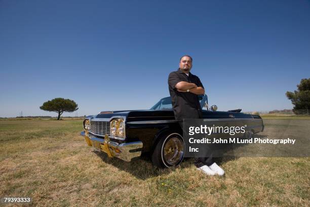 hispanic man leaning on low rider car - toughness man stock pictures, royalty-free photos & images