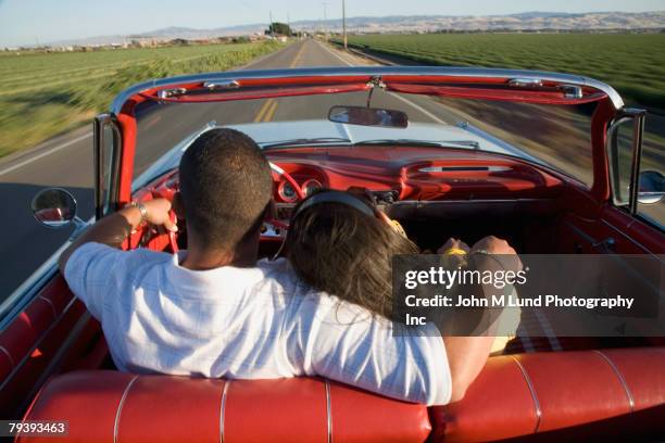 hispanic couple driving in convertible - driving romance stock-fotos und bilder