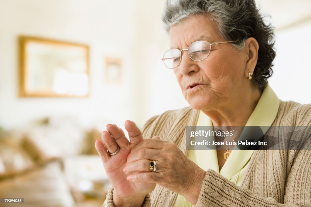 Senior Hispanic woman rubbing hand